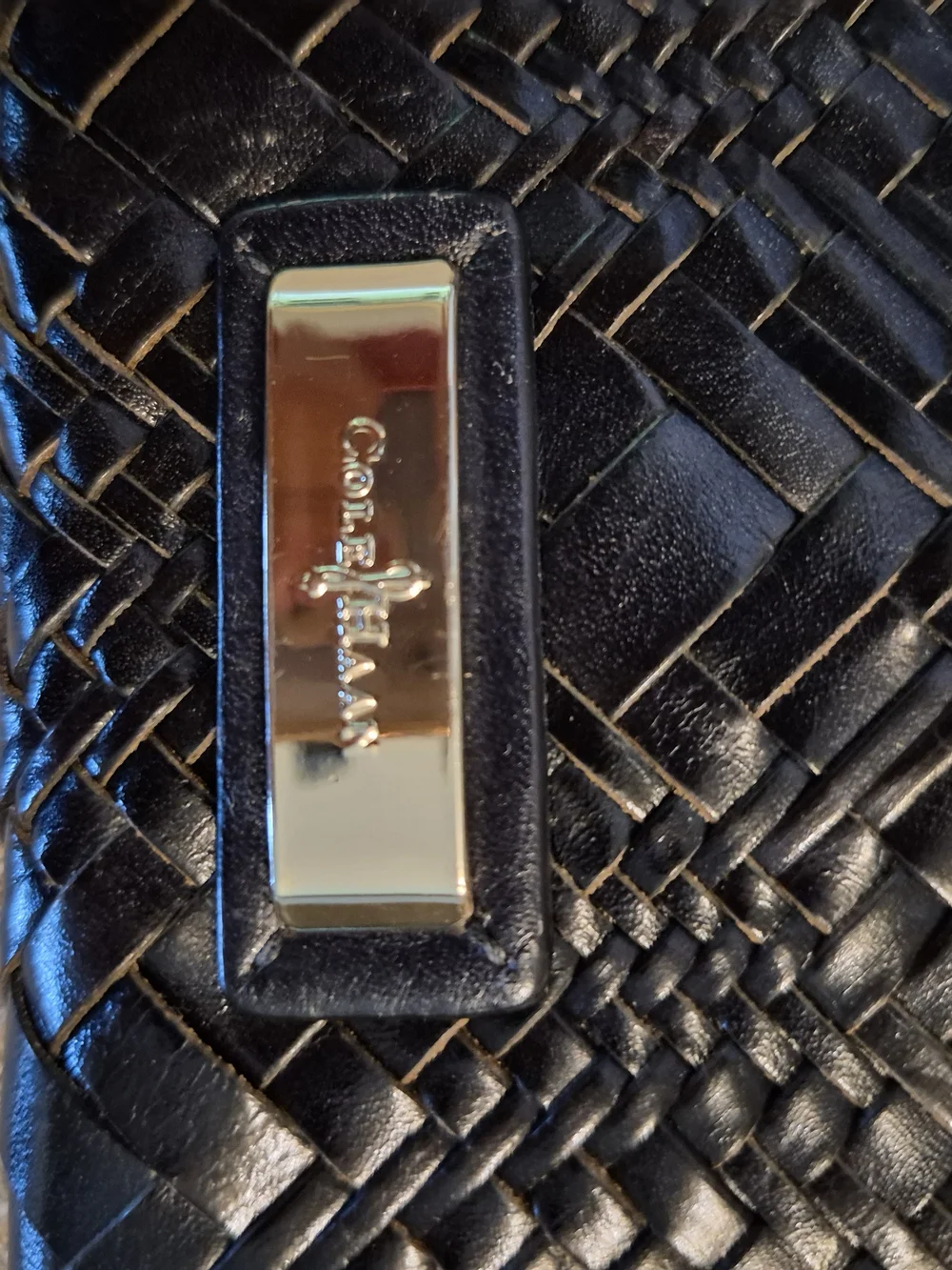 Cole Haan woven black leather clutch featuring a silver-tone logo emblem.